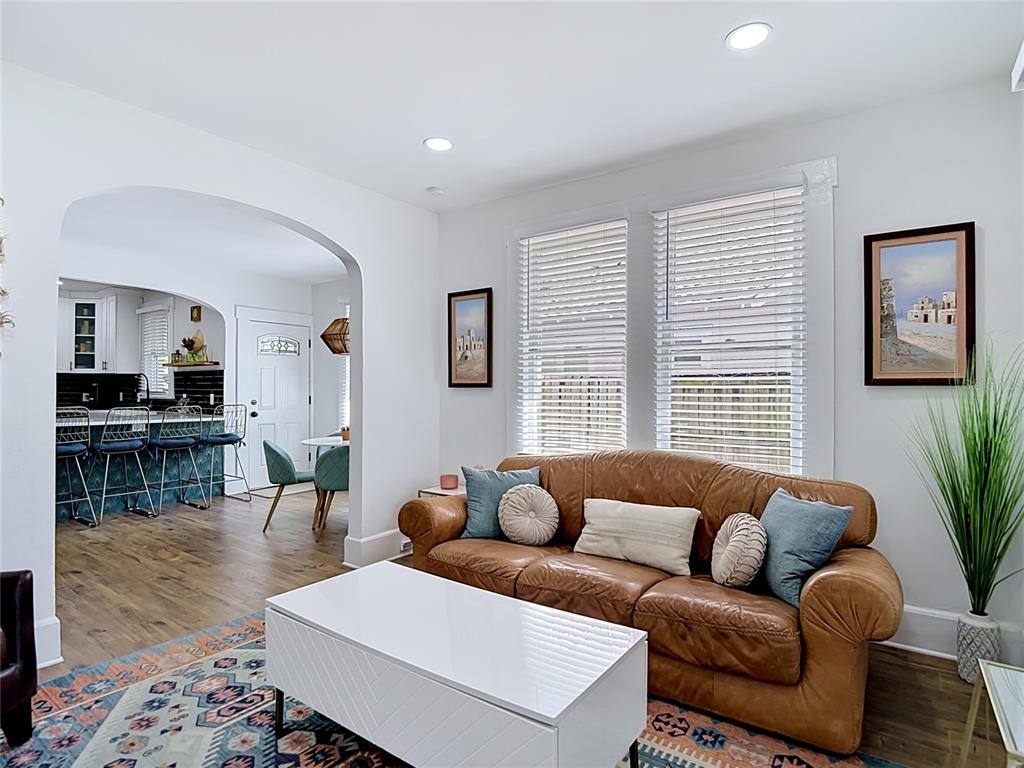 A living room with a brown leather sofa, white coffee table, and an arched entryway — 105 W ELM STREET, TAMPA, FL