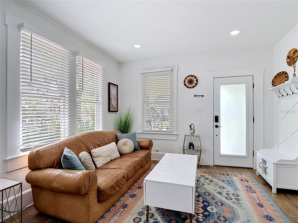 A living room features a brown leather sofa, white coffee table, and a patterned area rug — 105 W ELM STREET, TAMPA, FL