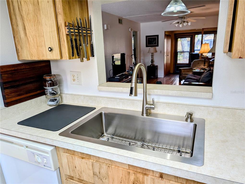 A kitchen sink with a stainless steel faucet sits in a countertop before a pass-through — 2808 60TH AVENUE W UNIT 1702, BRADENTON, FL
