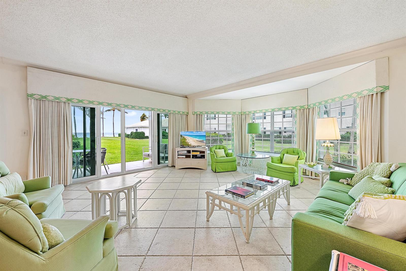 A living room features green furniture, tile flooring, and large sliding doors overlooking the ocean — 400 S Ocean Boulevard # 103a, Manalapan FL 33462, MANALAPAN, FL