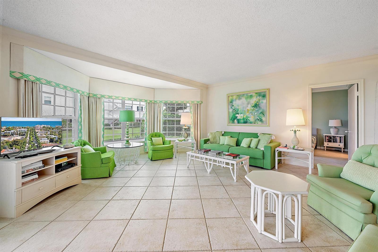 A living room with green furniture, tile flooring, and large windows overlooking a grassy area — 400 S Ocean Boulevard # 103a, Manalapan FL 33462, MANALAPAN, FL