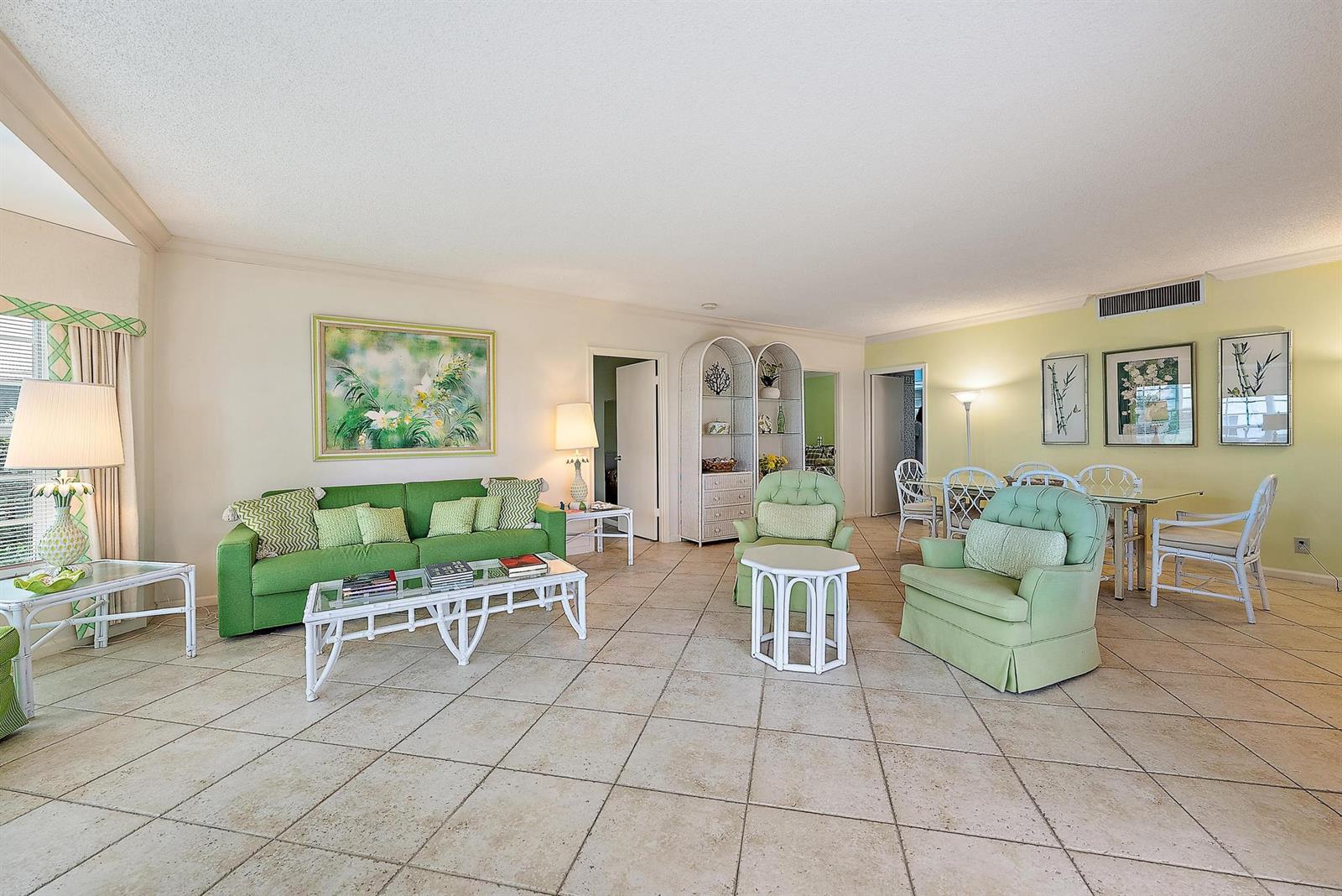 A spacious living and dining room features light tile floors, green furniture, and white accents — 400 S Ocean Boulevard # 103a, Manalapan FL 33462, MANALAPAN, FL