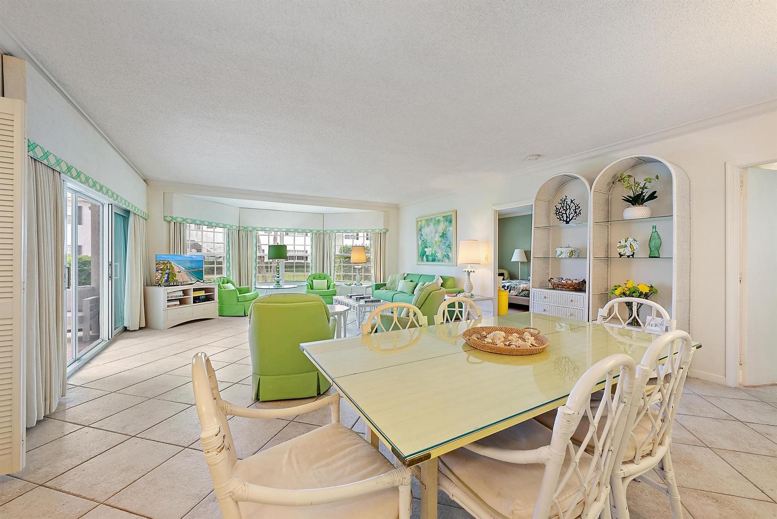 A bright living and dining area features tile floors, green furniture, and arched shelving units — 400 S Ocean Boulevard # 103a, Manalapan FL 33462, MANALAPAN, FL