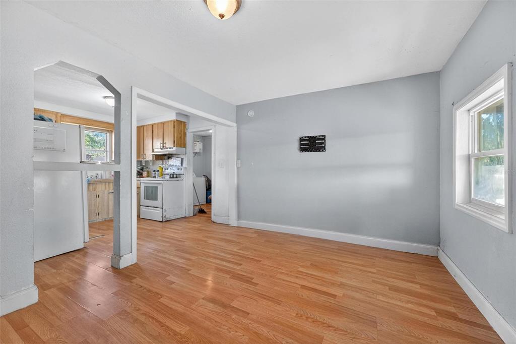 A dining area with light wood flooring and gray walls opens into a kitchen — 2206 SHIRAH ROAD, AUBURNDALE, FL