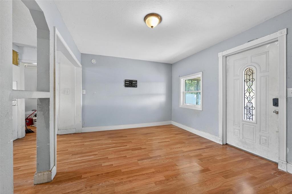 An empty room features light blue walls, hardwood flooring, a window, and a white door — 2206 SHIRAH ROAD, AUBURNDALE, FL