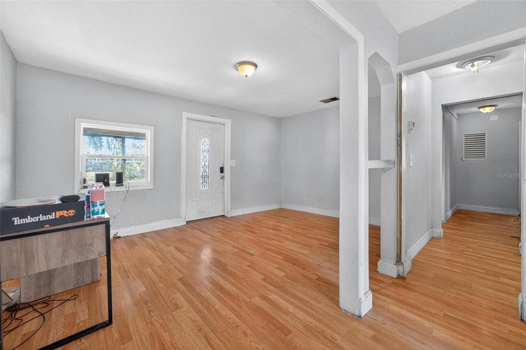 A room with light gray walls, wood-look flooring, and a white front door — 2206 SHIRAH ROAD, AUBURNDALE, FL
