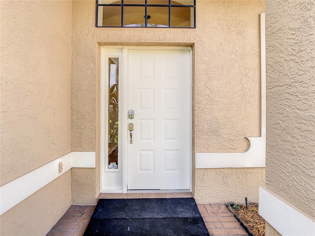 A white front door with a side window and transom window sits on a porch — 2811 BRANCH CREEK AVENUE, CLEARWATER, FL