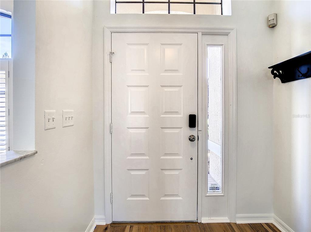 A white front door with a side window and a transom window above — 2811 BRANCH CREEK AVENUE, CLEARWATER, FL