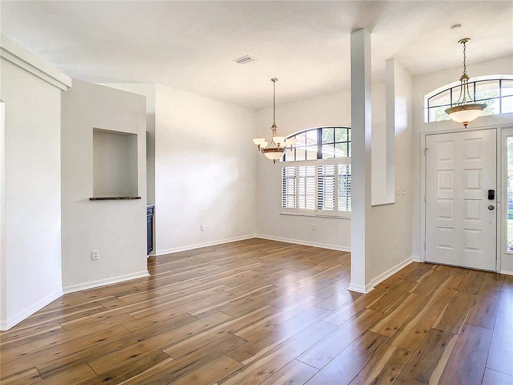 A dining area with wood-look tile flooring, a chandelier, and a white front door — 2811 BRANCH CREEK AVENUE, CLEARWATER, FL