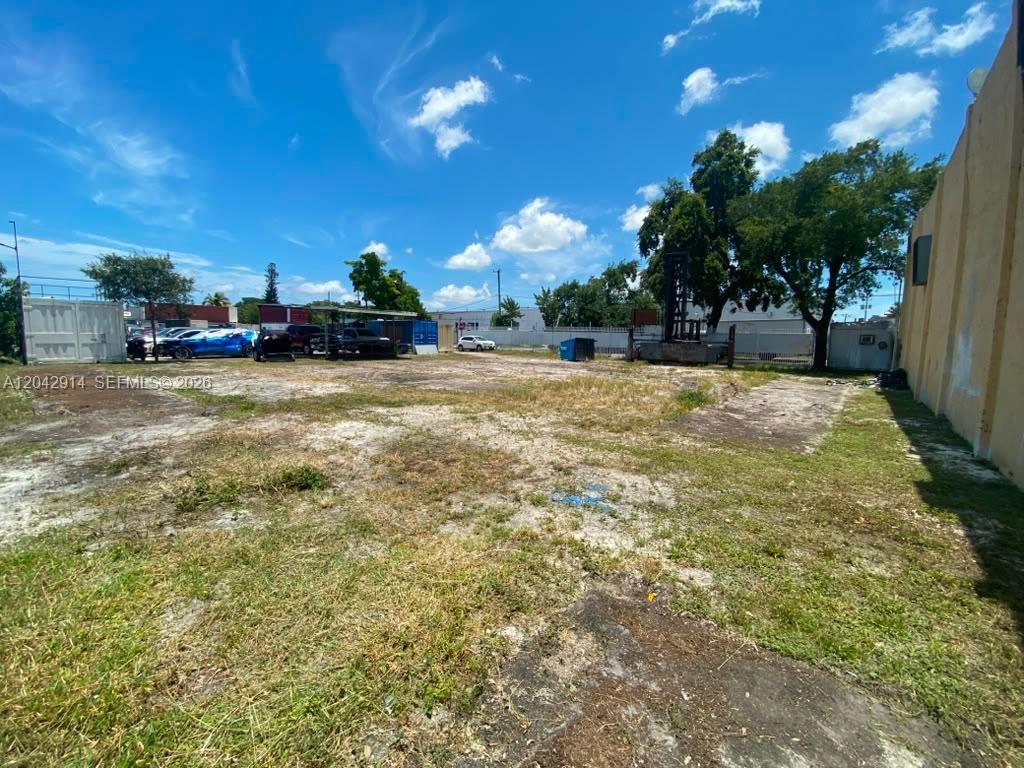 An empty, grassy lot with a concrete foundation and a building wall on the right — 3367 NW 68th St, Miami FL 33147, MIAMI, FL