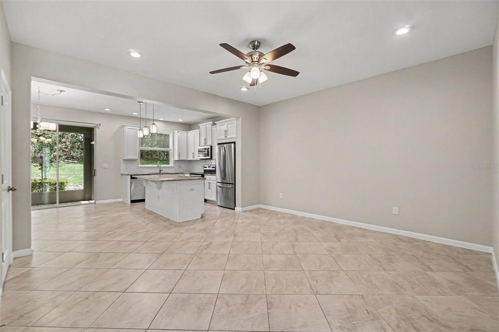 A spacious kitchen and dining area with tile flooring, white cabinetry, and a ceiling fan — 12411 TRAILHEAD DRIVE, BRADENTON, FL
