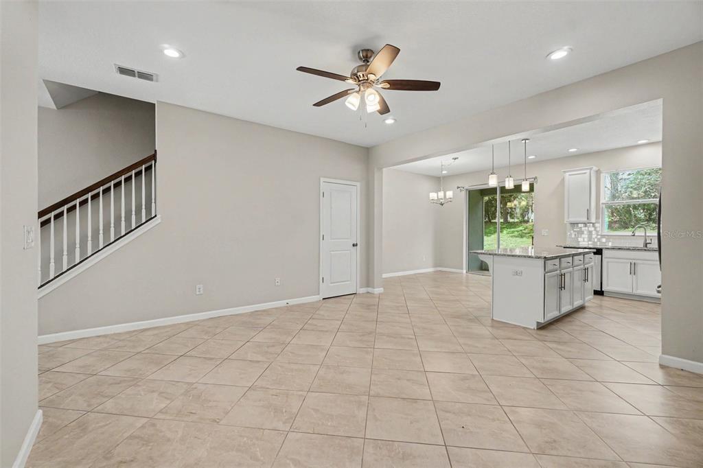 An open-concept living and kitchen area features tile flooring, a ceiling fan, and a staircase — 12411 TRAILHEAD DRIVE, BRADENTON, FL