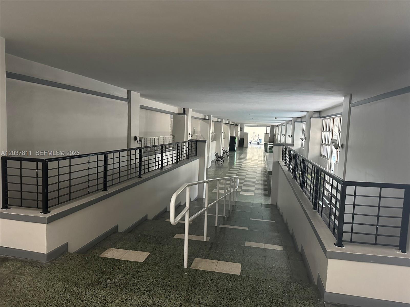 A covered outdoor walkway features a ramp with railings, tiled flooring, and black metal fencing — 7420 W 20th Ave # 452, Hialeah FL 33016, HIALEAH, FL