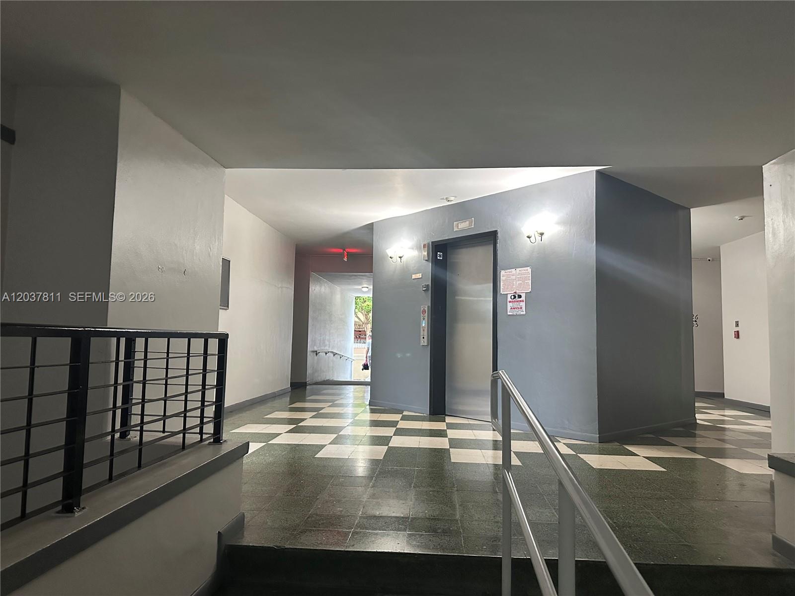 A hallway features a checkered tile floor, an elevator, and a metal railing — 7420 W 20th Ave # 452, Hialeah FL 33016, HIALEAH, FL