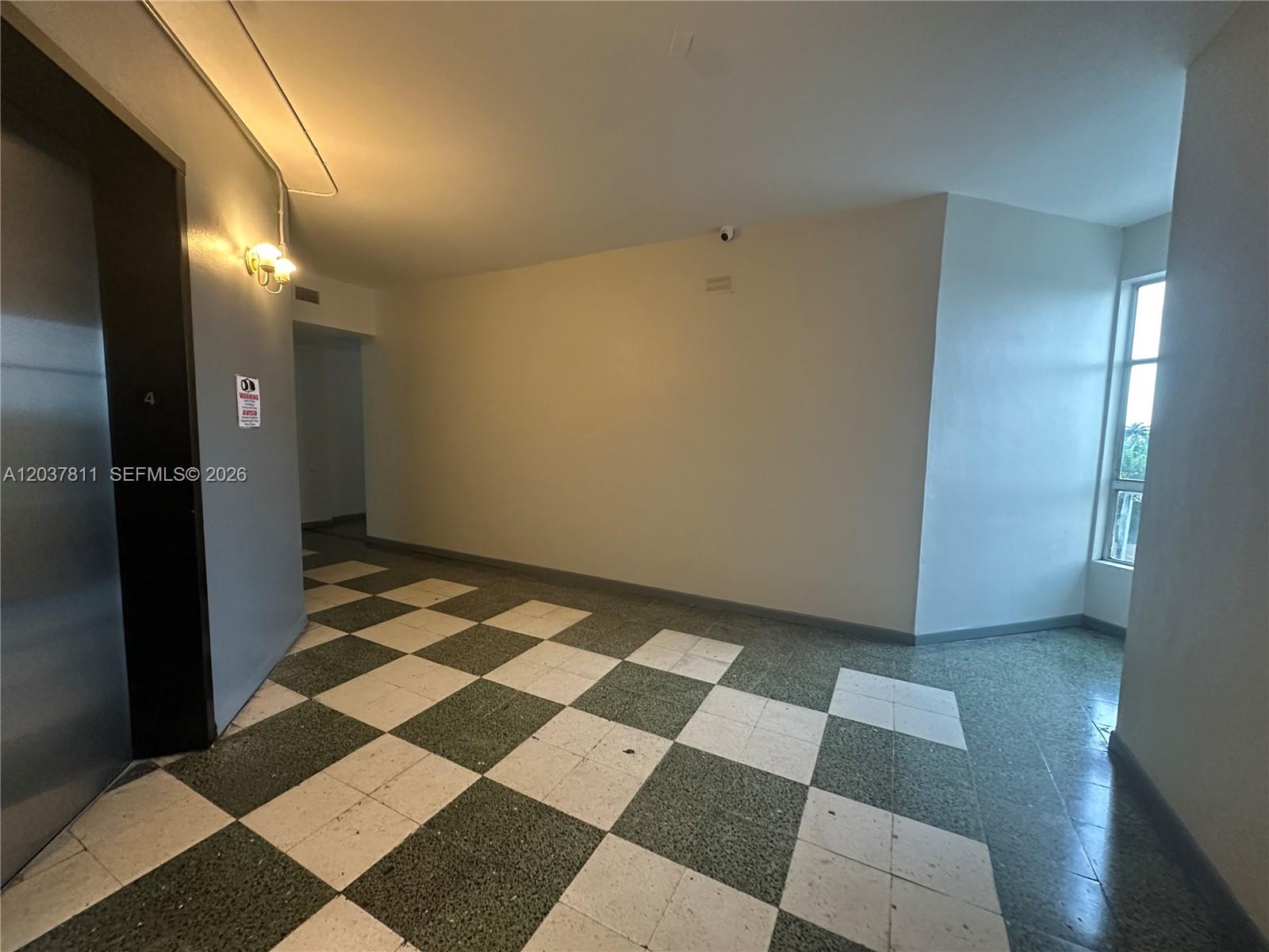 A hallway features a checkered tile floor, a metal elevator door, and a large window — 7420 W 20th Ave # 452, Hialeah FL 33016, HIALEAH, FL