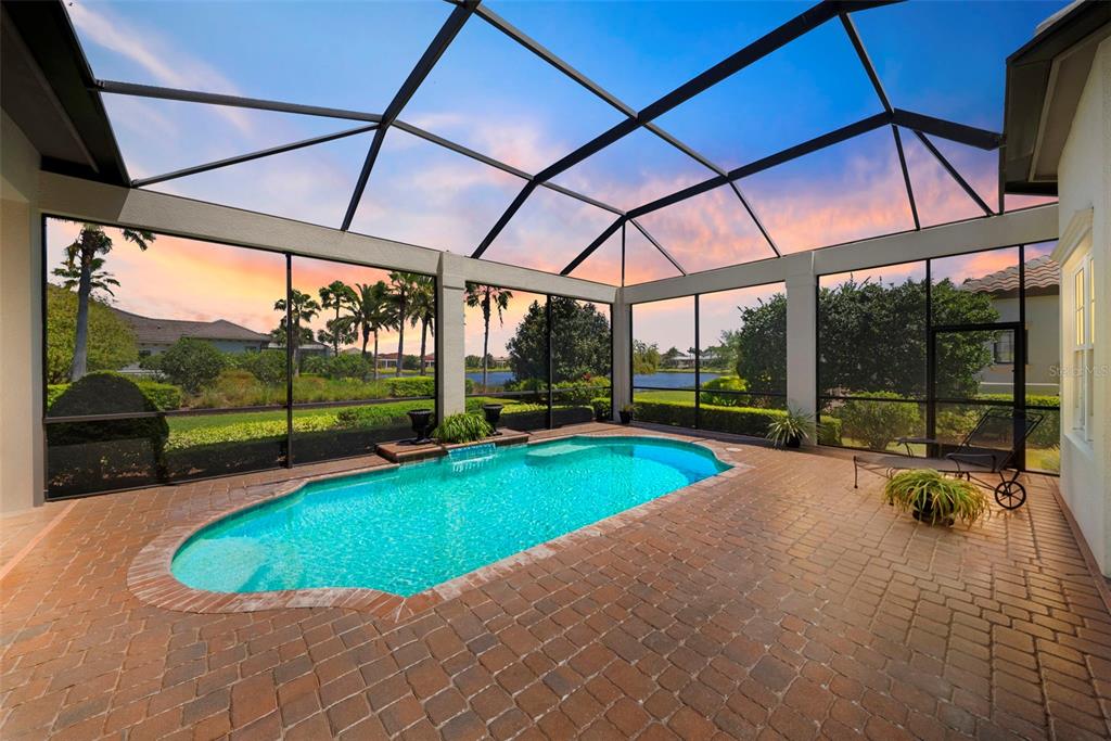A screened-in patio features a swimming pool with a water feature and brick pavers — 16204 DAYSAILOR TRAIL, LAKEWOOD RANCH, FL