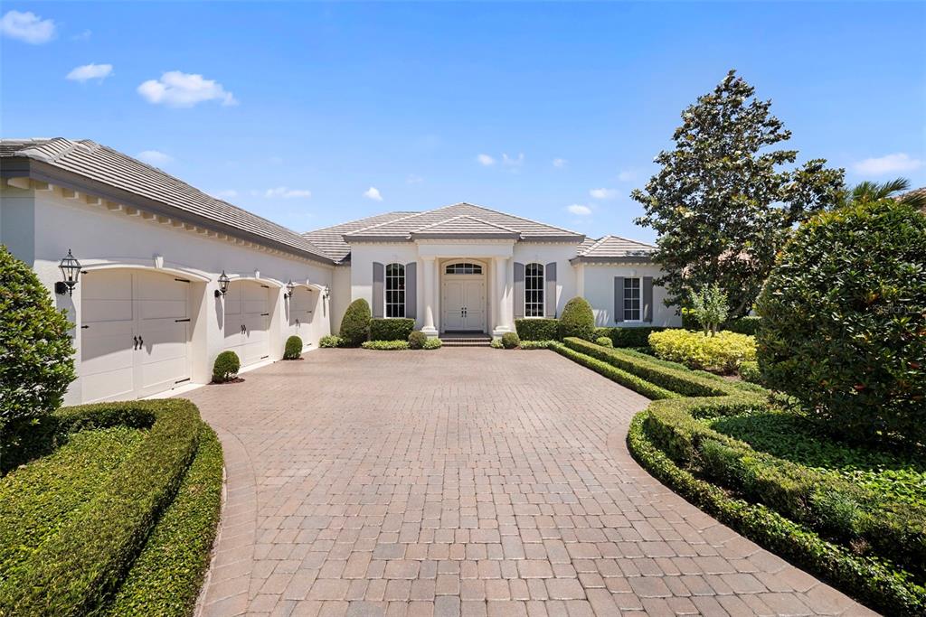 A single-story house with a three-car garage and a paved driveway surrounded by hedges — 16204 DAYSAILOR TRAIL, LAKEWOOD RANCH, FL