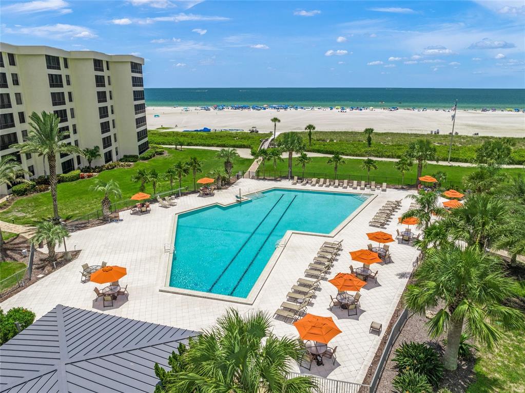 An aerial view of a swimming pool with orange umbrellas next to a beach — 5780 MIDNIGHT PASS ROAD UNIT B105, SARASOTA, FL