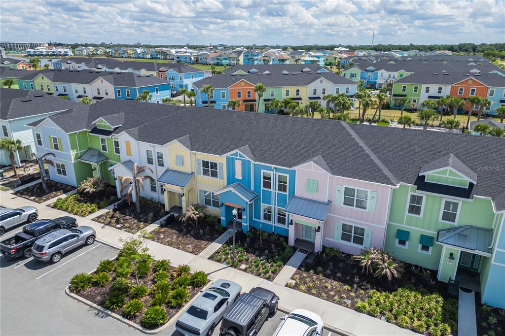 An aerial view shows a row of colorful, multi-story townhouses with dark shingled roofs — 2915 CASTAWAY LANE, KISSIMMEE, FL