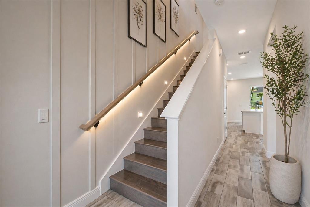 A staircase with wood treads and a lighted handrail sits beside a hallway with tile — 2915 CASTAWAY LANE, KISSIMMEE, FL