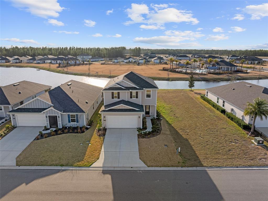 An aerial view shows a two-story suburban house with a driveway and adjacent vacant lot — 55 CAMELLIA STREET, PALM COAST, FL