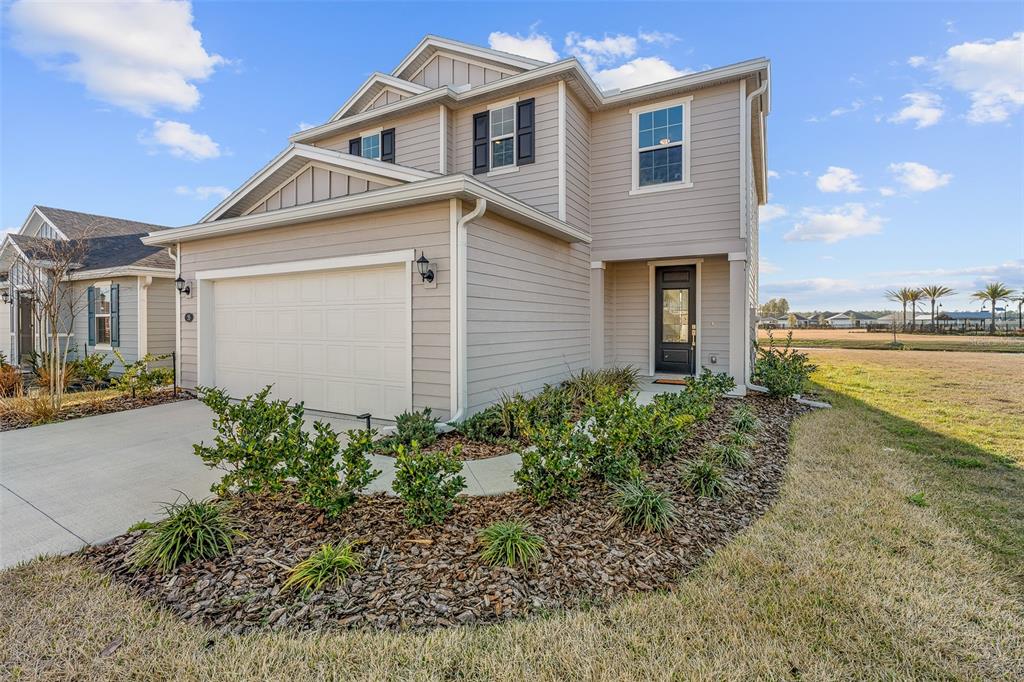 A two-story house with light gray siding, a two-car garage, and a landscaped front yard — 55 CAMELLIA STREET, PALM COAST, FL