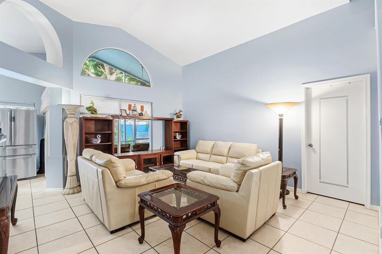 A living room features light blue walls, tile flooring, cream leather sofas, and vaulted ceilings — 143 St Michaels Court, Jupiter FL 33458, JUPITER, FL