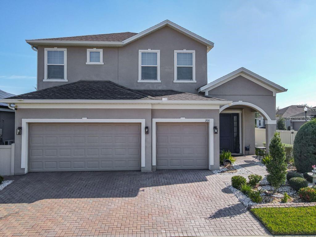 A two-story house with a gray stucco exterior, a three-car garage, and a paved driveway — 200 TRINITY RIDGE CIRCLE, DAVENPORT, FL