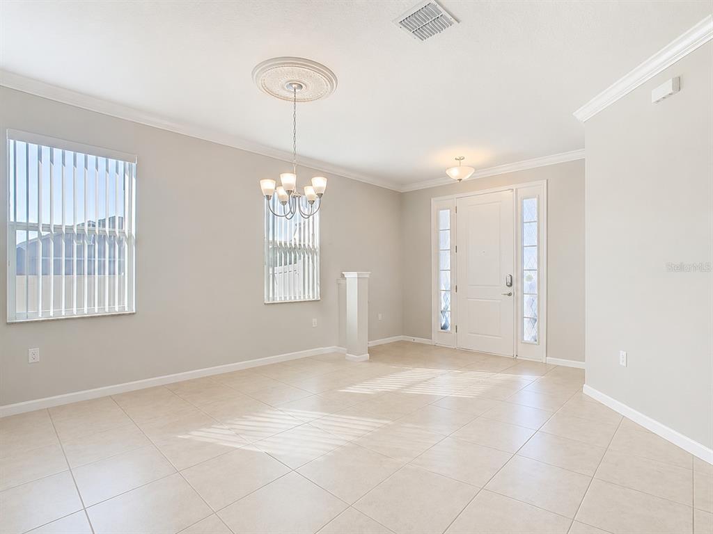 An empty dining room with tile floors, a chandelier, and a front entryway — 200 TRINITY RIDGE CIRCLE, DAVENPORT, FL