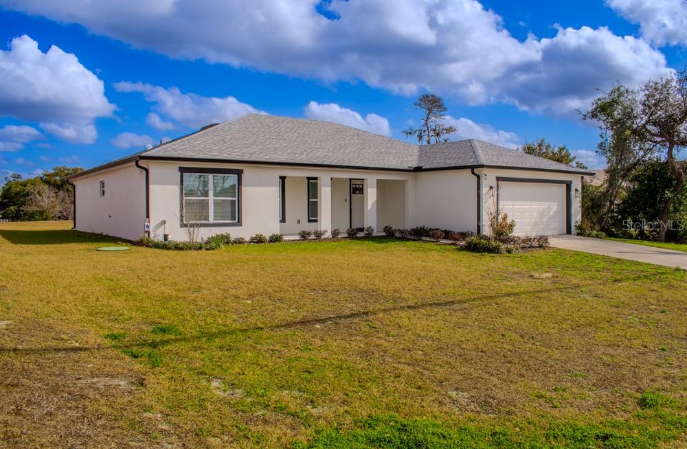 A single-story house with a white stucco exterior, dark trim, and an attached two-car garage — 5104 KIRKWOOD AVENUE, SPRING HILL, FL