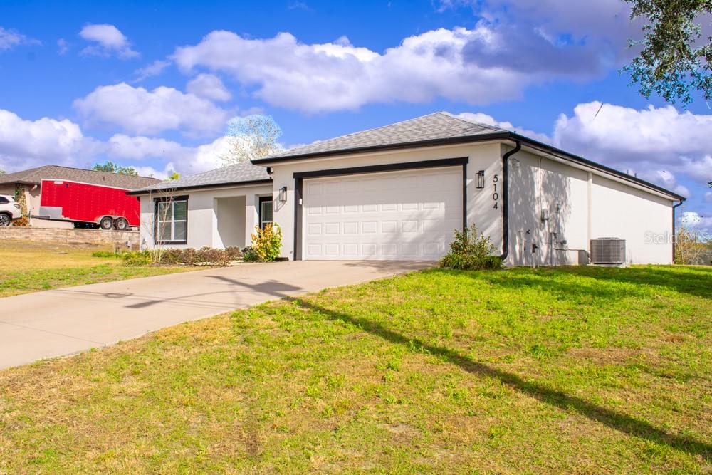 A single-story house with a white exterior, a two-car garage, and a concrete driveway — 5104 KIRKWOOD AVENUE, SPRING HILL, FL