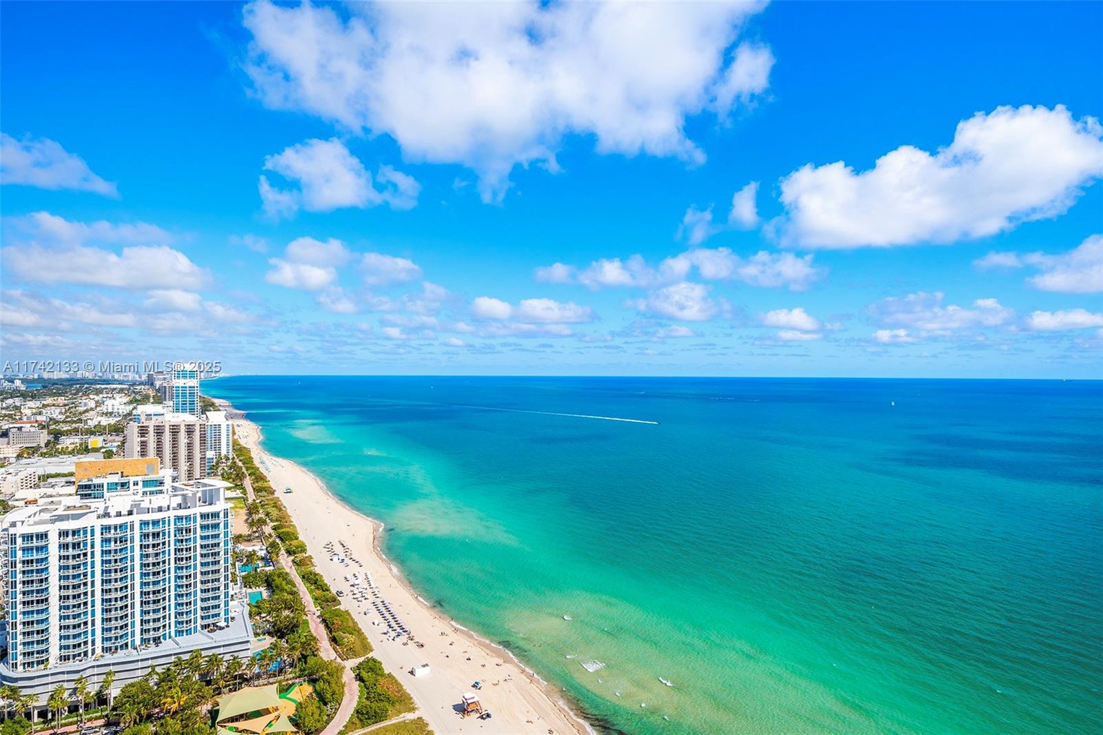 An aerial view shows a sandy beach along a turquoise ocean with high-rise buildings nearby — 6365 Collins Ave # 3801, Miami Beach FL 33141, MIAMI BEACH, FL