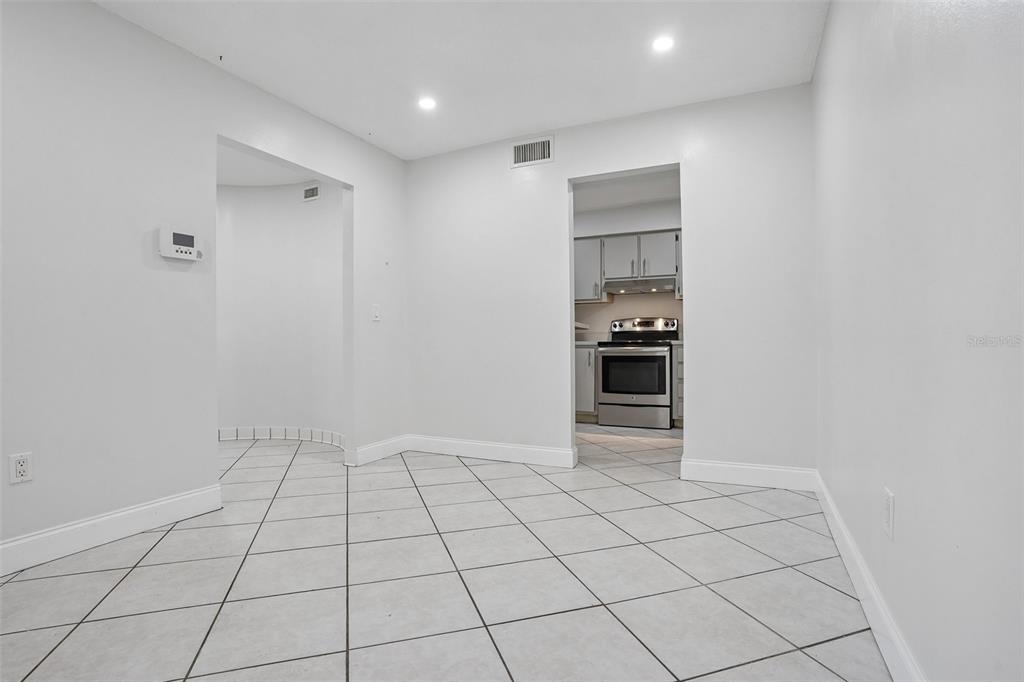 A dining area with white walls and light-colored diagonal floor tiles leads to a kitchen — 546 ORANGE DRIVE UNIT 13, ALTAMONTE SPRINGS, FL
