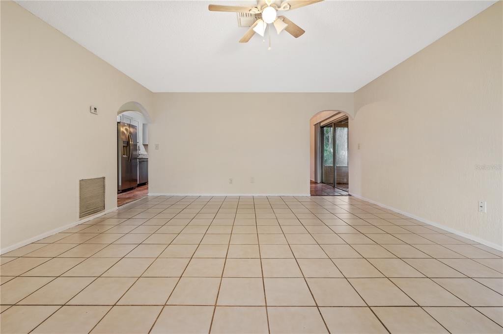 A spacious room with beige tile flooring, light-colored walls, and a ceiling fan — 8529 RENALD BOULEVARD, TEMPLE TERRACE, FL