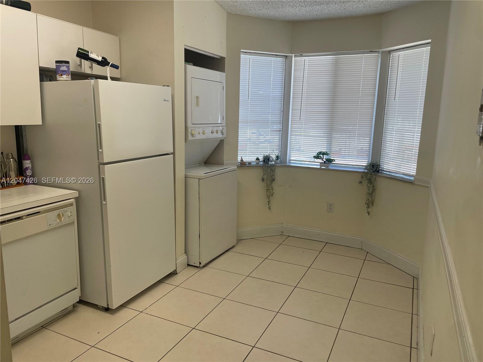 A kitchen features white appliances, a stacked washer and dryer, and a bay window — 15400 SW 134th Pl # 404, Miami FL 33177, MIAMI, FL