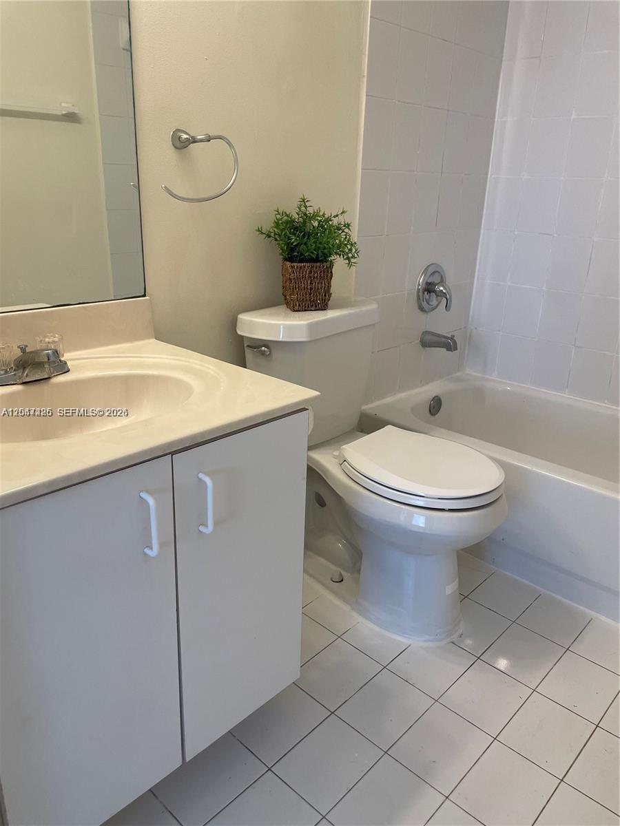 A bathroom features a white vanity, a toilet, and a tiled bathtub shower combination — 15400 SW 134th Pl # 404, Miami FL 33177, MIAMI, FL