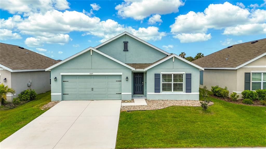 A single-story house with a light green exterior, a two-car garage, and a front lawn — 5209 SONG SPARROW TERRACE, PALMETTO, FL