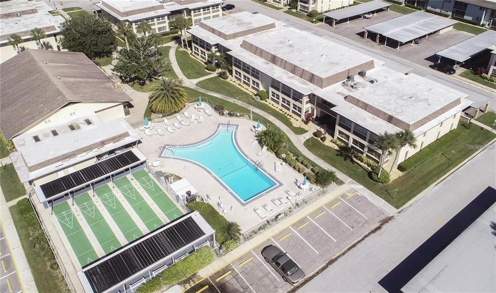 An aerial view shows an apartment complex with a swimming pool and shuffleboard courts — 5111 AMULET DRIVE UNIT 208, NEW PORT RICHEY, FL