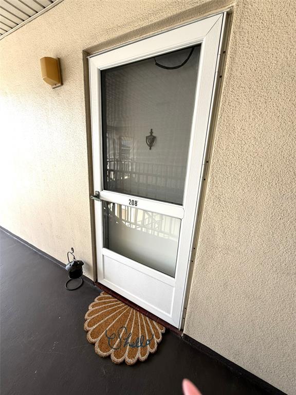 A white storm door with the number 208 is installed on a beige exterior wall — 5111 AMULET DRIVE UNIT 208, NEW PORT RICHEY, FL
