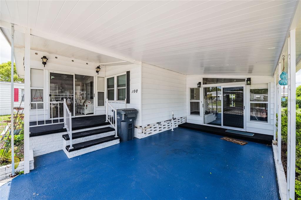 A mobile home exterior features a blue painted carport, a covered porch, and white siding — 1610 REYNOLDS RD. UNIT 108, LAKELAND, FL