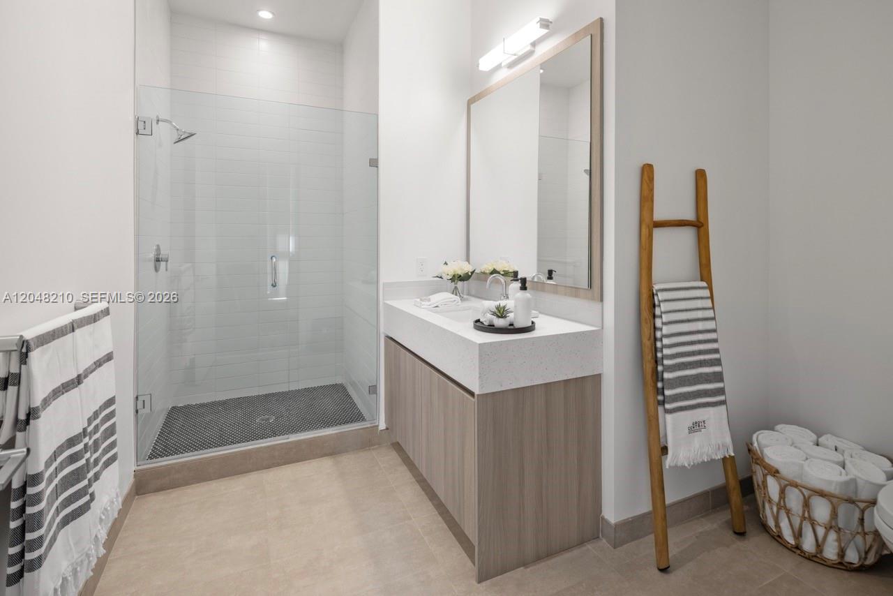 A modern bathroom features a glass-enclosed shower, a wood vanity, and a towel ladder — 2800 SW 27th Terrace # 0513, Miami FL 33133, MIAMI, FL