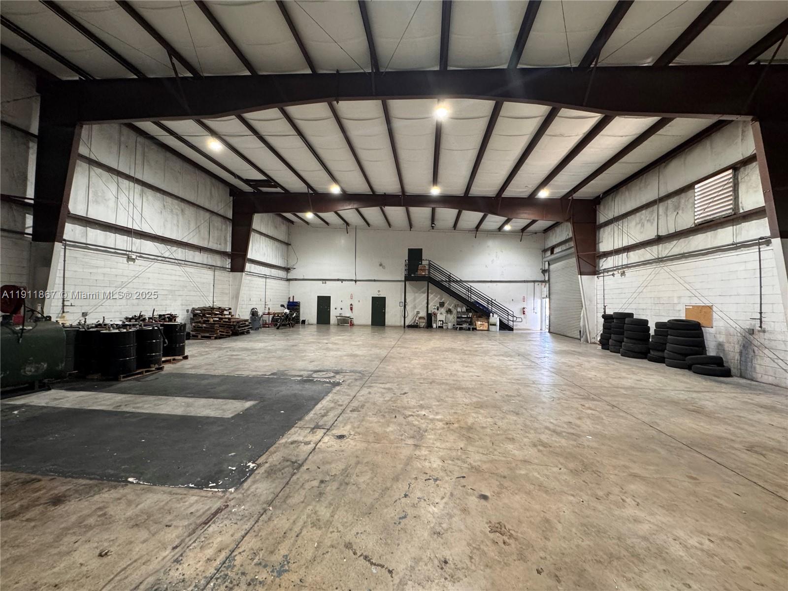 A large, open industrial warehouse features concrete floors, exposed steel beams, and a metal staircase — 5909 Anno Ave, Orlando FL 32809, ORLANDO, FL