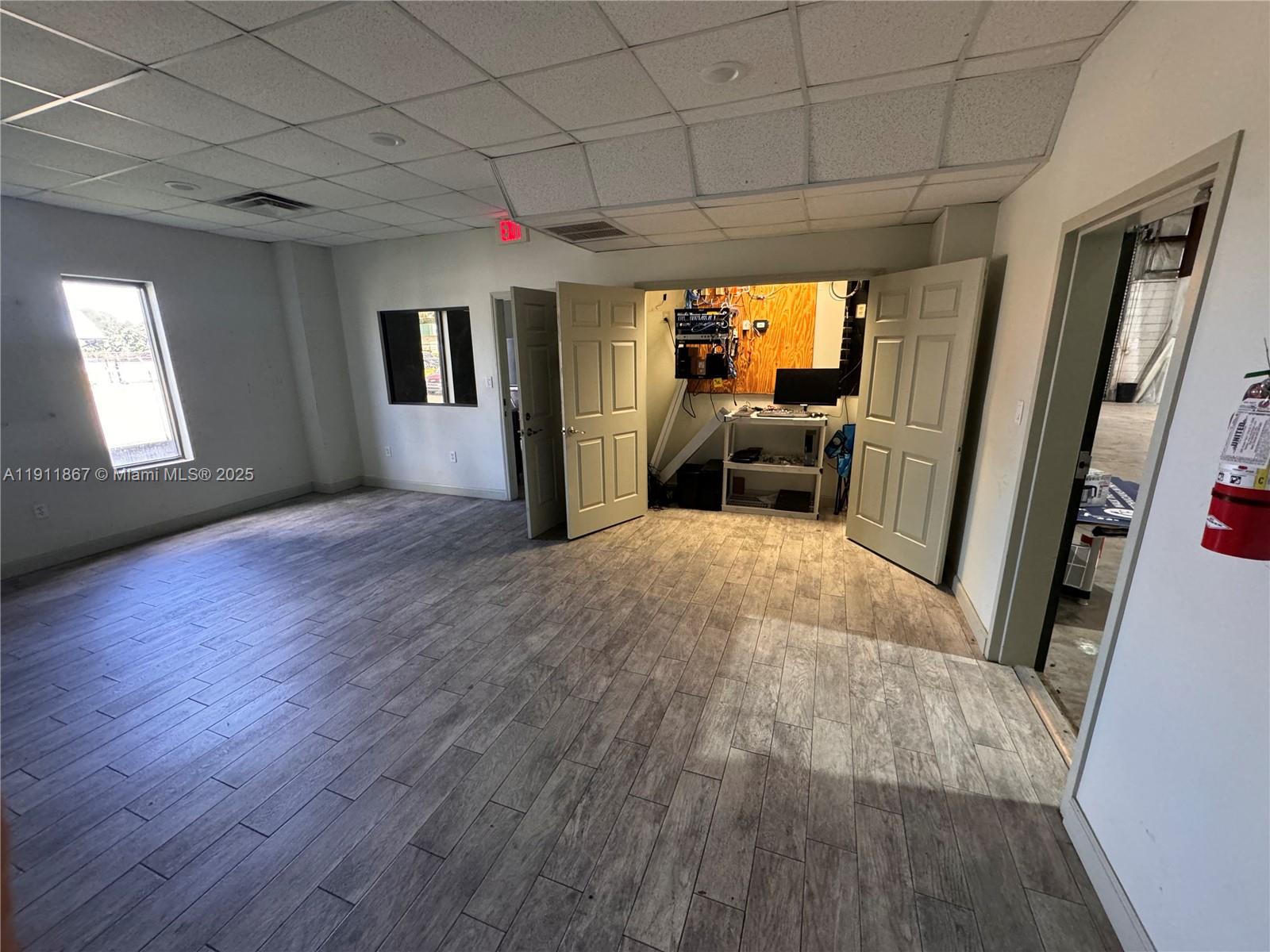 An office room features wood-look tile flooring, a drop ceiling, and an open utility closet — 5909 Anno Ave, Orlando FL 32809, ORLANDO, FL
