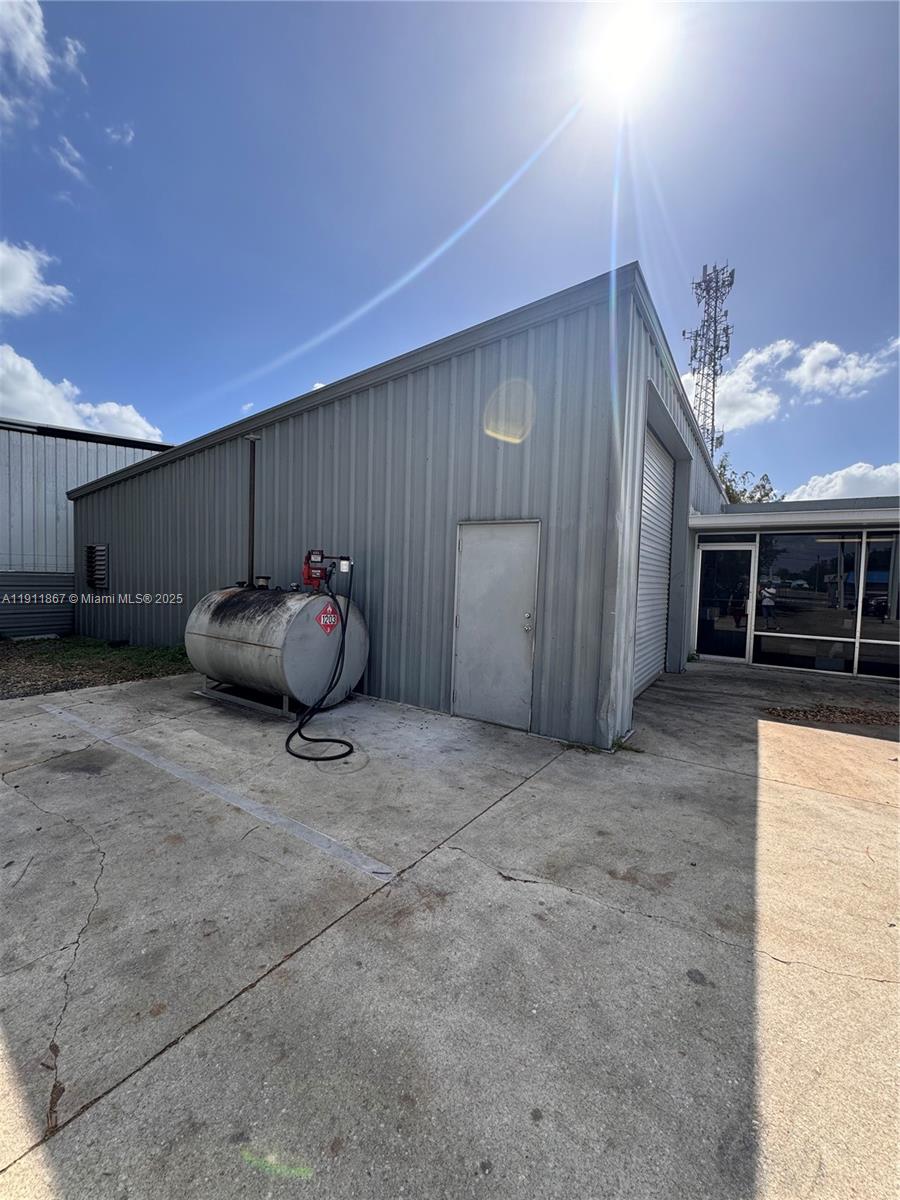 An exterior view of a metal warehouse building featuring a fuel tank and glass entrance — 5909 Anno Ave, Orlando FL 32809, ORLANDO, FL