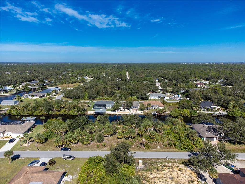 An aerial view shows a residential canal-front neighborhood with houses, trees, and a paved road — 17340 GULFSPRAY CIRCLE, PORT CHARLOTTE, FL