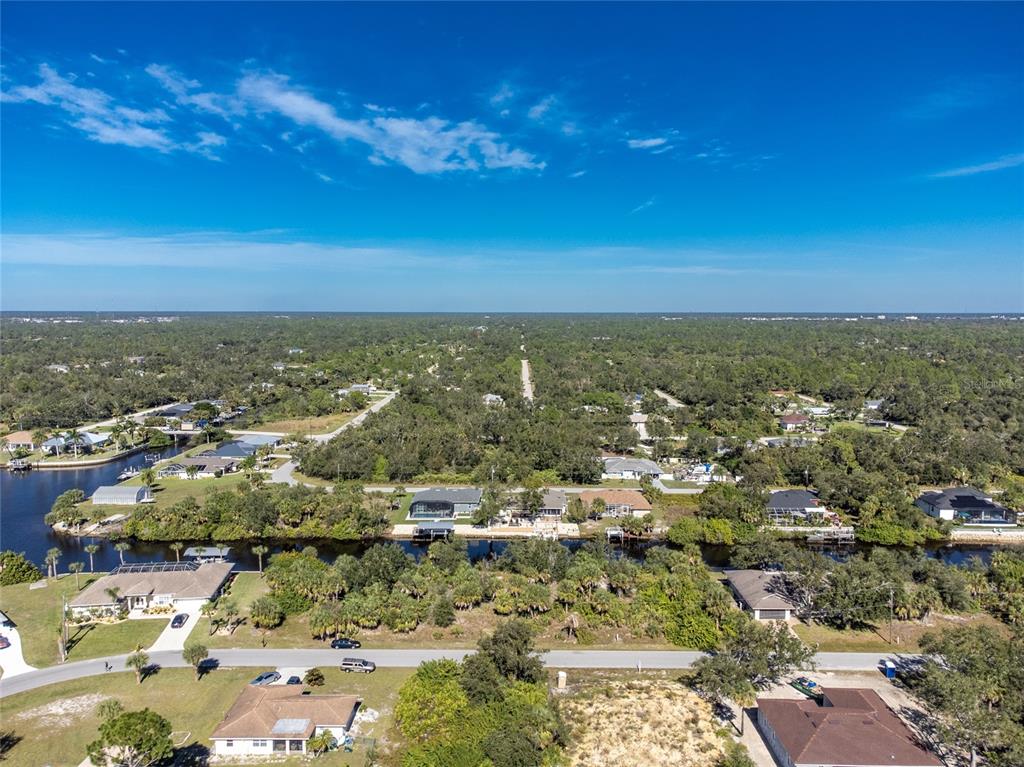 An aerial view shows houses along a canal surrounded by dense trees and vegetation — 17340 GULFSPRAY CIRCLE, PORT CHARLOTTE, FL
