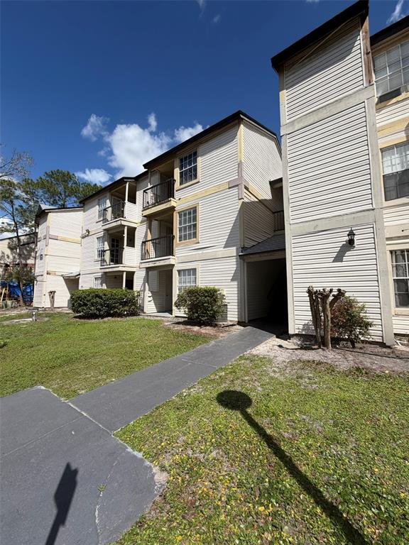 A multi-story apartment building with beige siding, balconies, and a concrete walkway — 1940 LAKE ATRIUMS CIRCLE UNIT 110, ORLANDO, FL