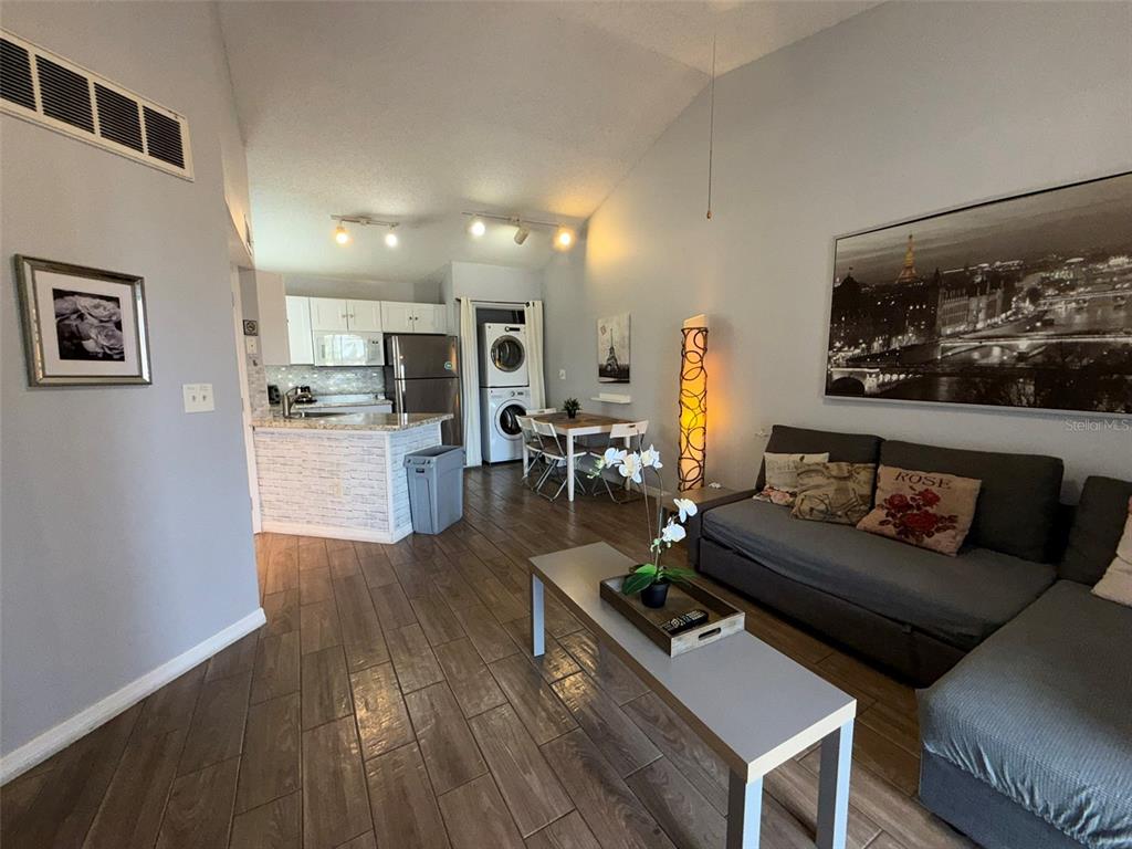 An open-concept living room features a kitchen, dining area, and gray sectional sofa — 1940 LAKE ATRIUMS CIRCLE UNIT 110, ORLANDO, FL