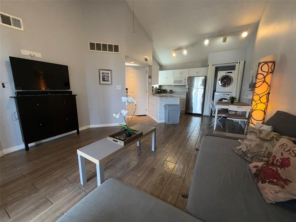 This open-concept living area features a kitchen, dining space, and laundry closet with tile flooring — 1940 LAKE ATRIUMS CIRCLE UNIT 110, ORLANDO, FL
