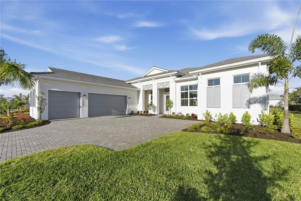 A single-story house with a three-car garage, white stucco exterior, and a paved driveway — 8065 NEVIS RUN, BRADENTON, FL